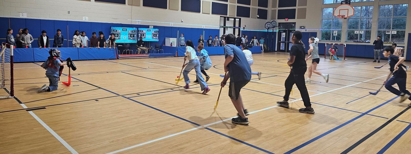 Kids playing gym floor hockey.