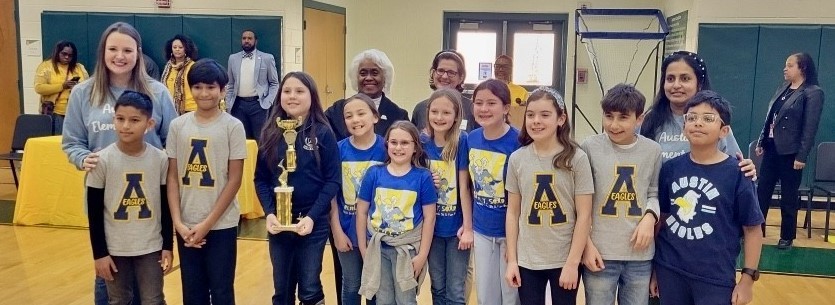 14 people posing with a 1st place trophy in a gymnasium