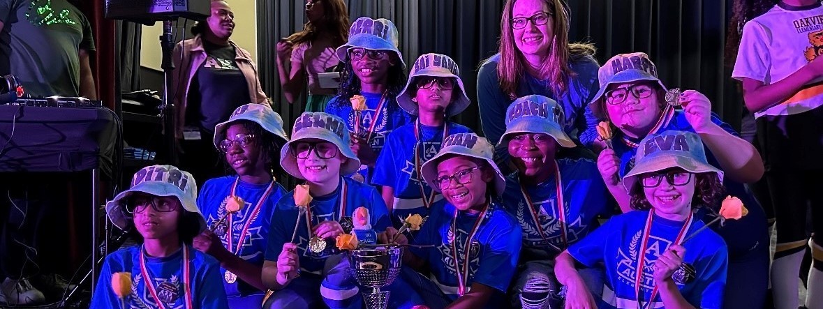 9 girls and 2 adults posing with medals