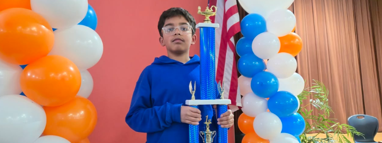 a boy holding a trophy with balloons in the background