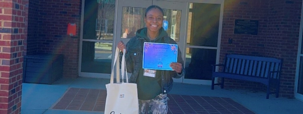 Teacher holding a certificate and Canva bag.